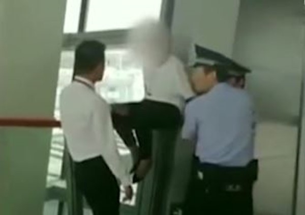 遲到被拒登機女乘客爬上欄杆與警員「對峙」。(網圖)