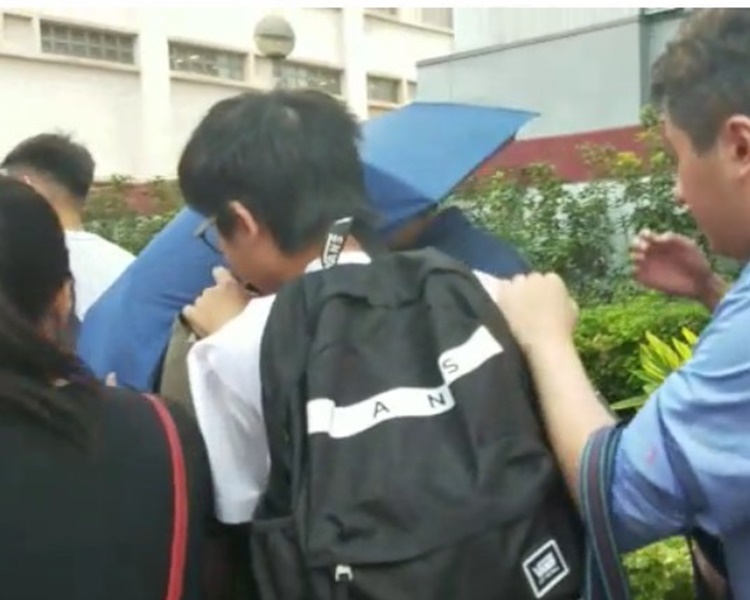 謝灼華持雨傘在朋友簇擁保護下離開法庭。陳楚琨攝