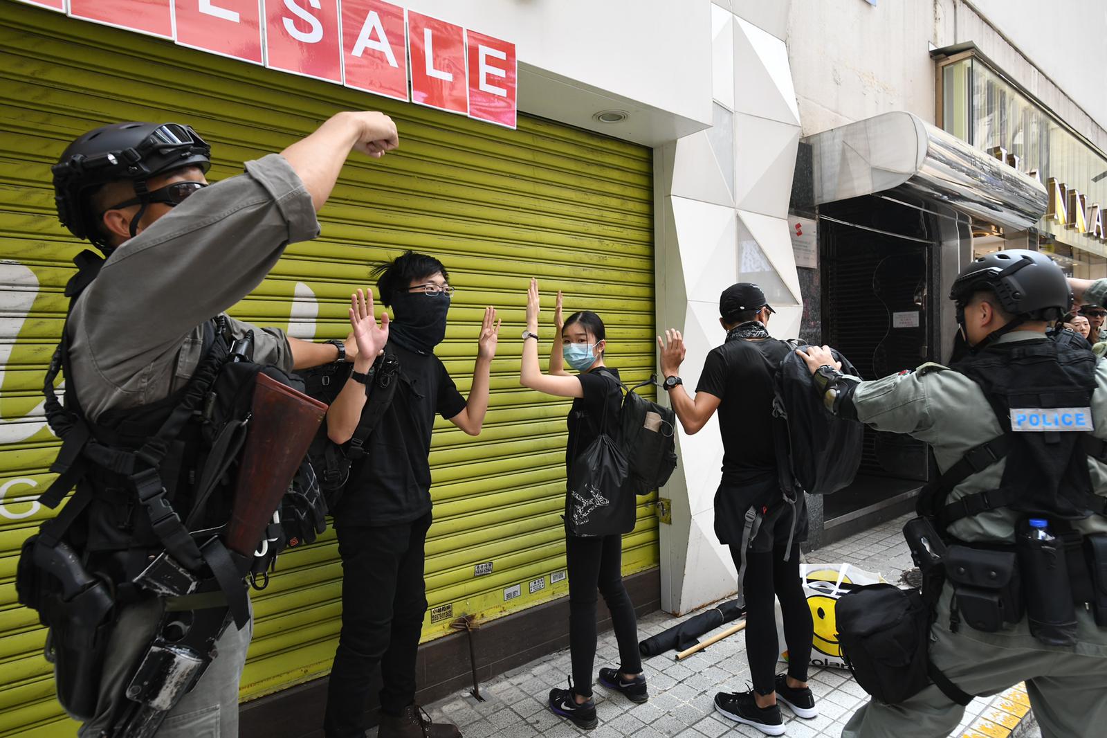 防暴警搜查在場的黑衣人士。