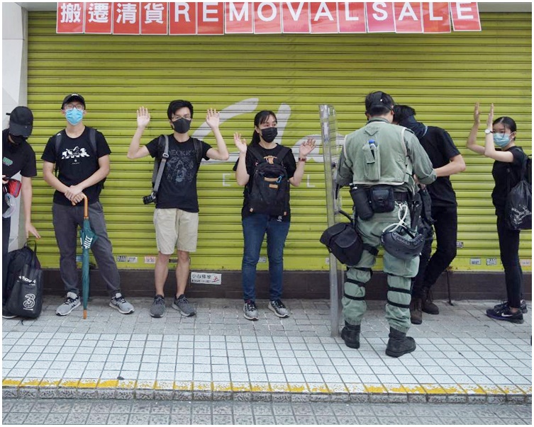 防暴警搜查在場的黑衣人士。