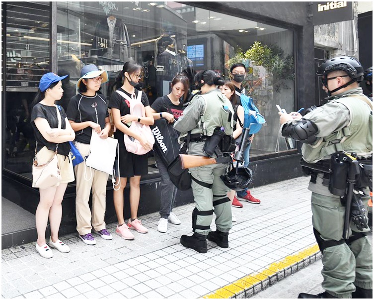 防暴警搜查在場的黑衣人士。