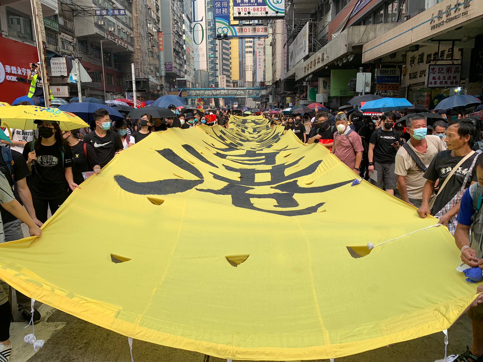 有人帶同一幅黃底黑字巨型直幡遊行。