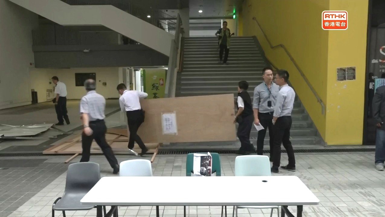 有職員清理被破壞的圍板。港台截圖