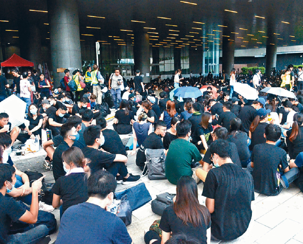 ■立法會外坐滿示威者，大部份人都穿着黑色上衣，並席地而坐休息。p/　　