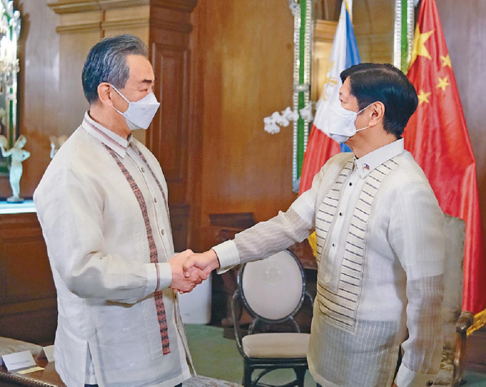 ■王毅（左）穿上菲律賓國服，與小馬可斯握手。