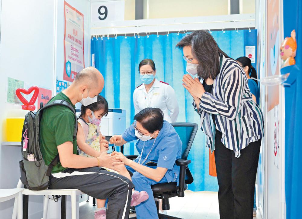 ■一名兩歲幼童早前到兒童醫院接種新冠疫苗，公務員事務局局長楊何蓓茵（右一）在旁鼓勵。資料圖片