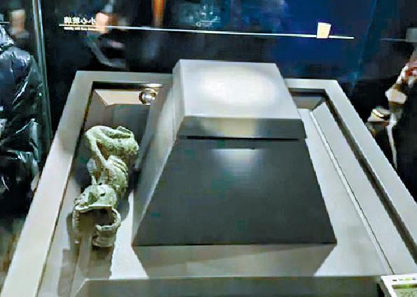 ■銅像被撞後掉落至展示台下的平台，打橫躺着。