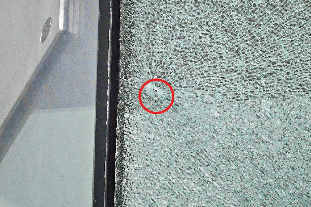 ■西九龍裁判法院玻璃幕牆疑遭射擊，玻璃爆裂有小孔（紅圈示）。